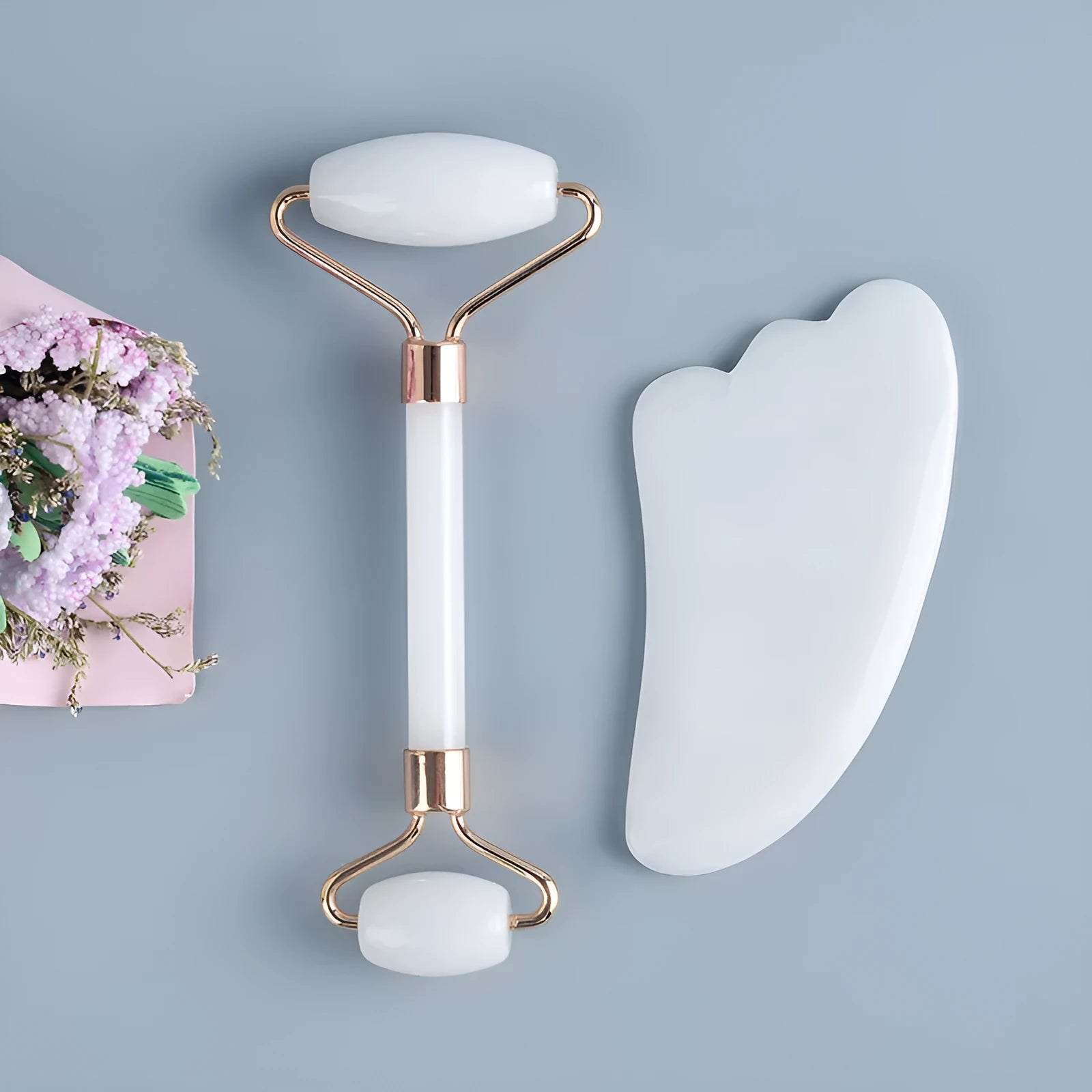 White jade double-headed facial roller and gua sha scraping tools on wooden storage board