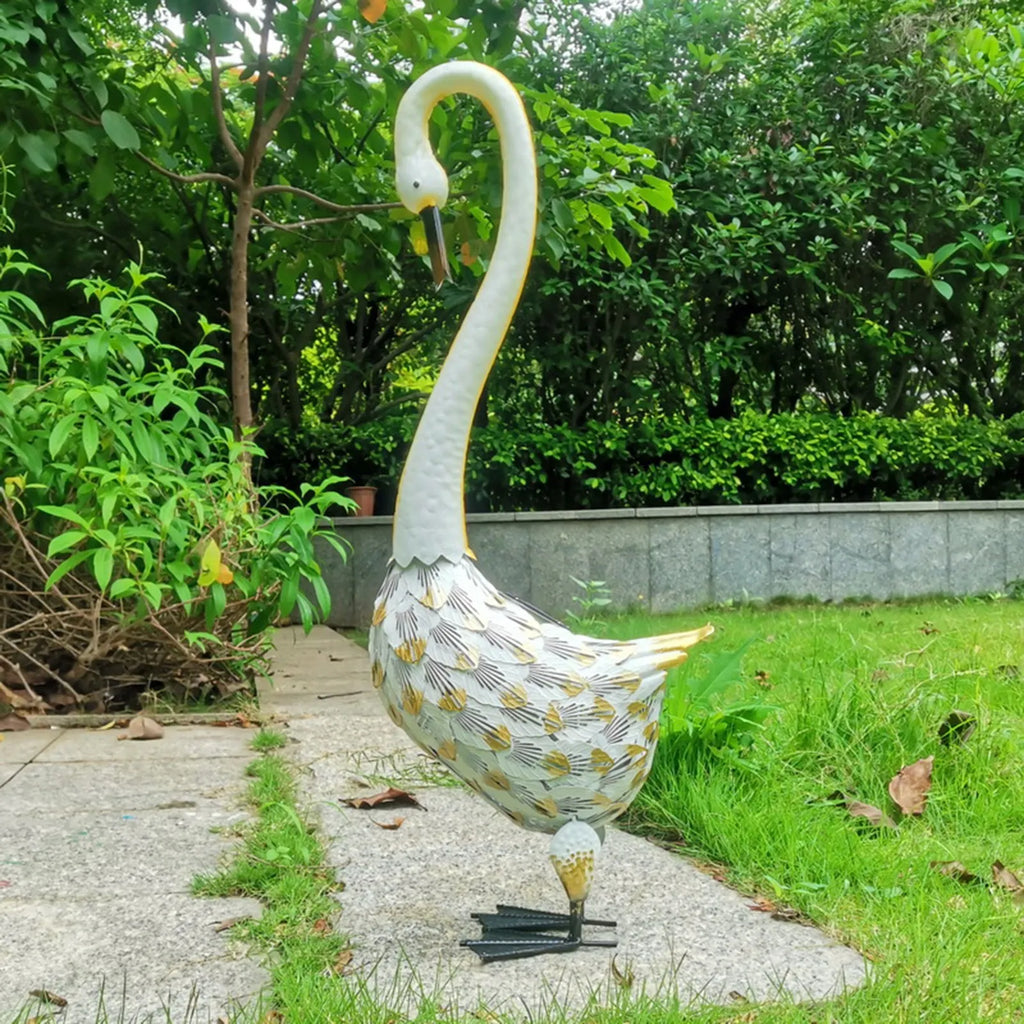 Iron wrought swan solar garden light on lawn at dusk with warm white glow
