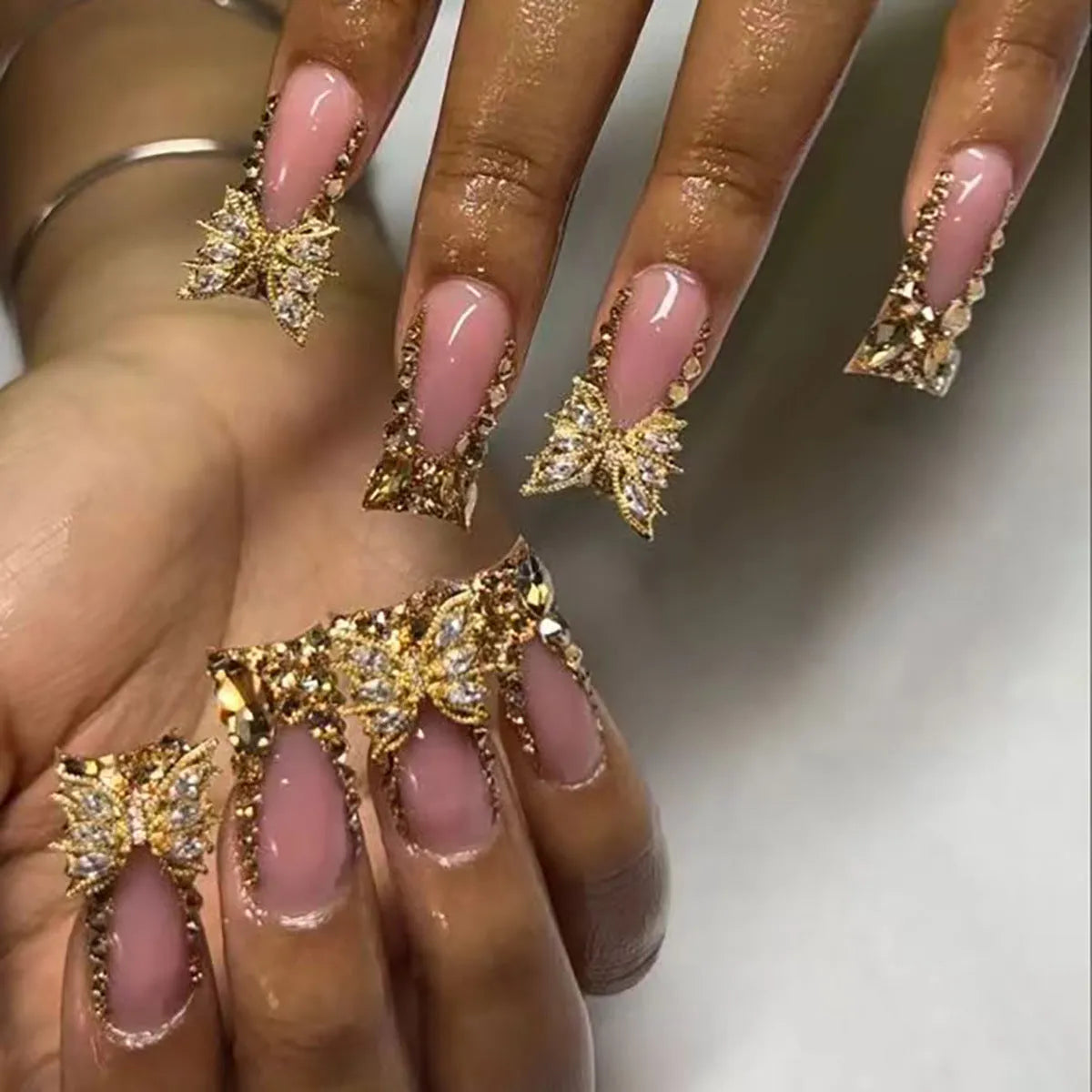Pack of 24 golden diamond and debris-style butterfly nail stickers with a bottle of glue.