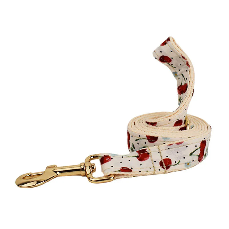 Red cherry print dog collar set with matching leash, vest, and light gold buckle
