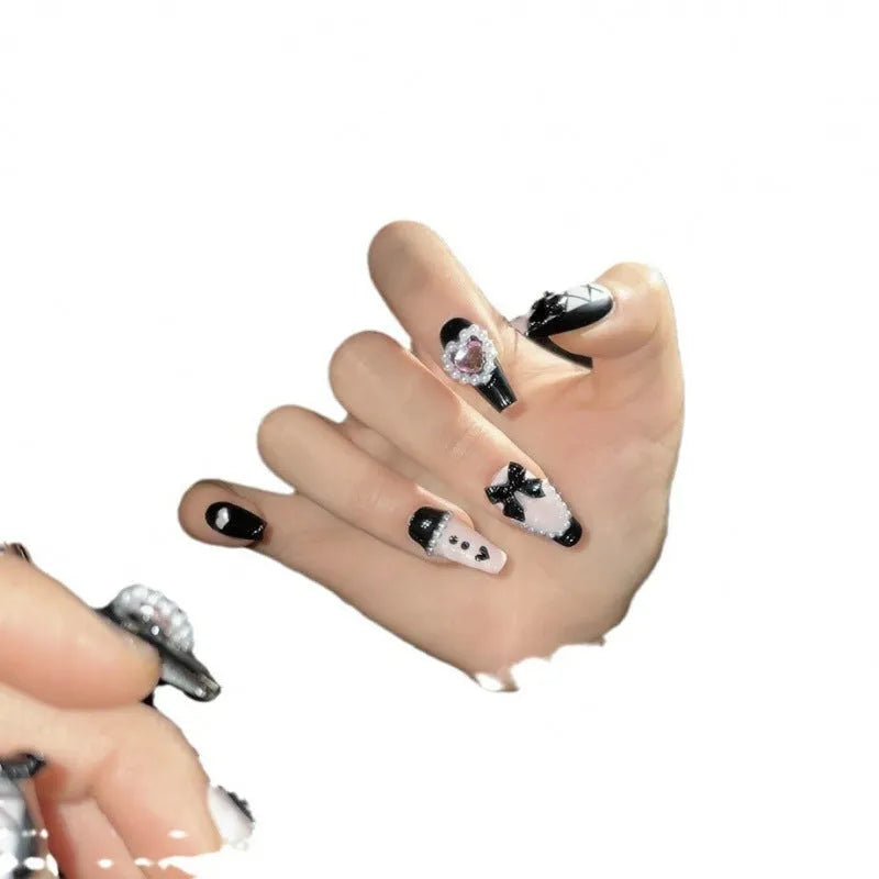 Handmade artificial nails with black and pink heart design and bow pattern in four sizes