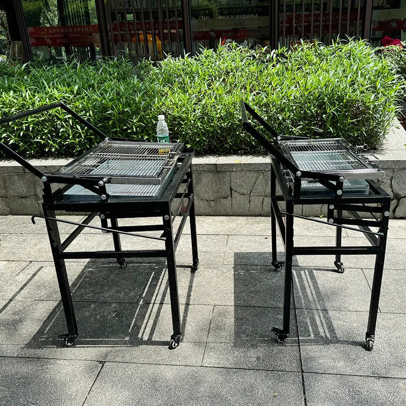 Large portable charcoal barbecue grill with a foldable metal frame set up in a garden.