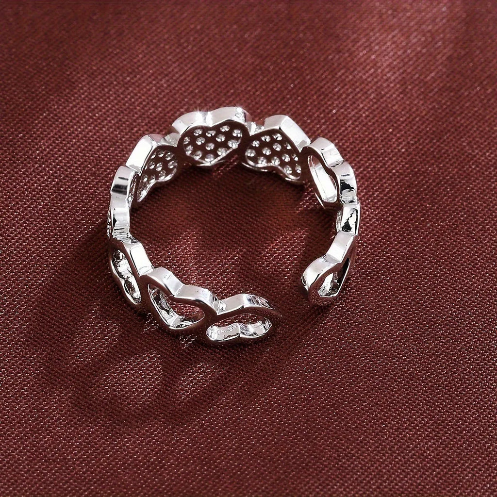 Gold and silver adjustable heart-shaped couples ring on a small finger.