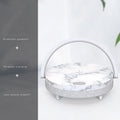 White wireless charging Bluetooth speaker and LED night light unit with phone holder on marble pattern base.