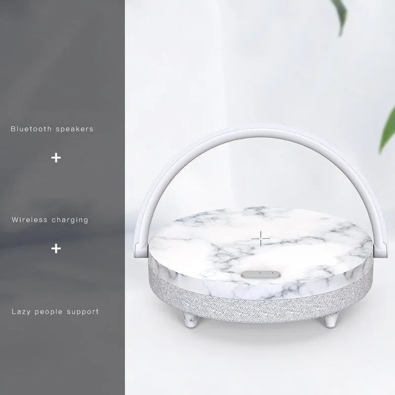 White wireless charging Bluetooth speaker and LED night light unit with phone holder on marble pattern base.