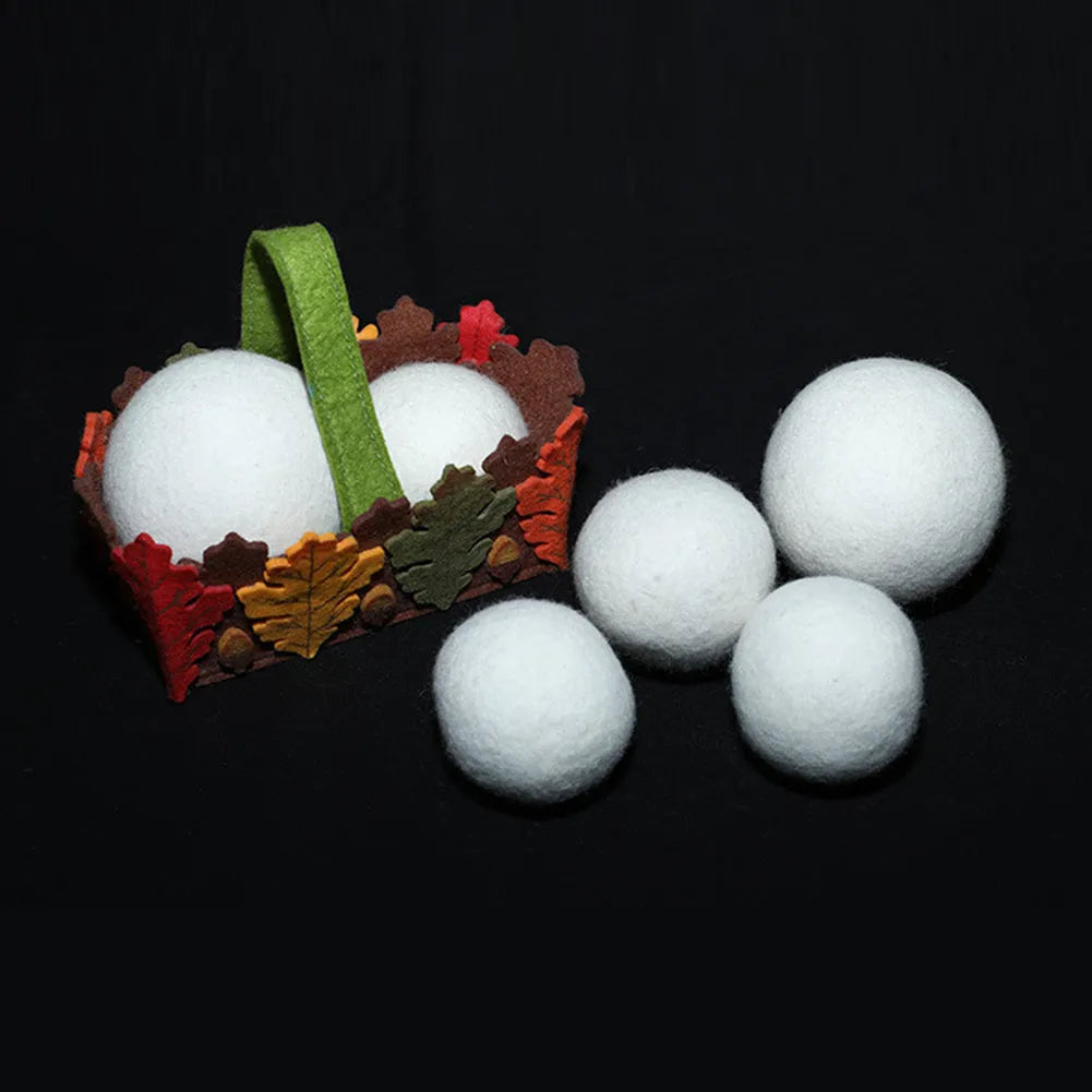 A natural wool drying ball for tumble dryers next to a plain cotton storage bag on a laundry background.
