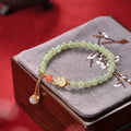 Jade women's bracelet with gold-plated fu character and a central gourd charm on wrist.
