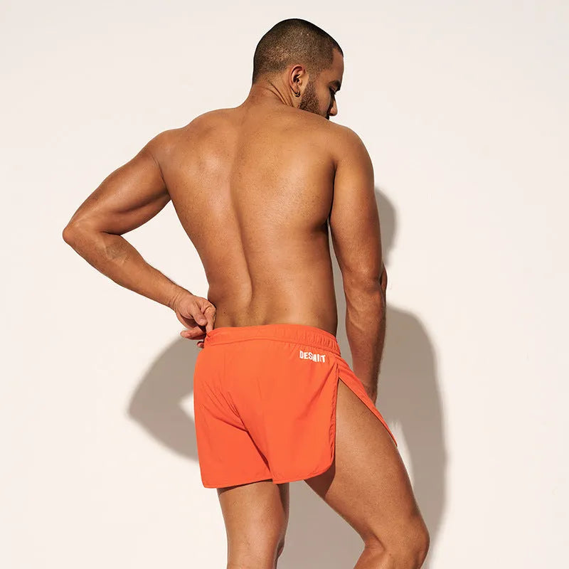 Men's loose-fitting beach shorts in orange, fluorescent green, and black colours on a size chart background