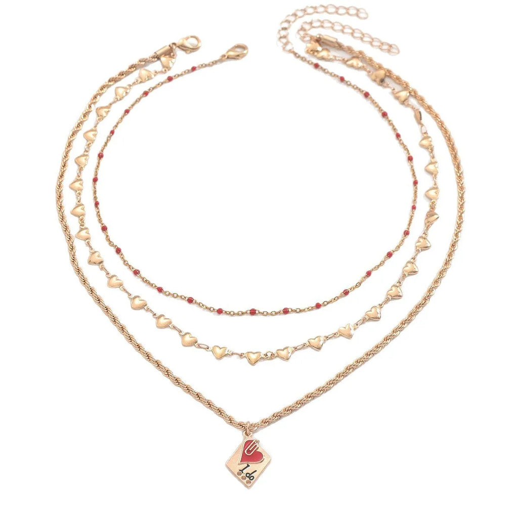Close-up of a silver-toned three-layer necklace with small geometric heart pendants on an adjustable chain.