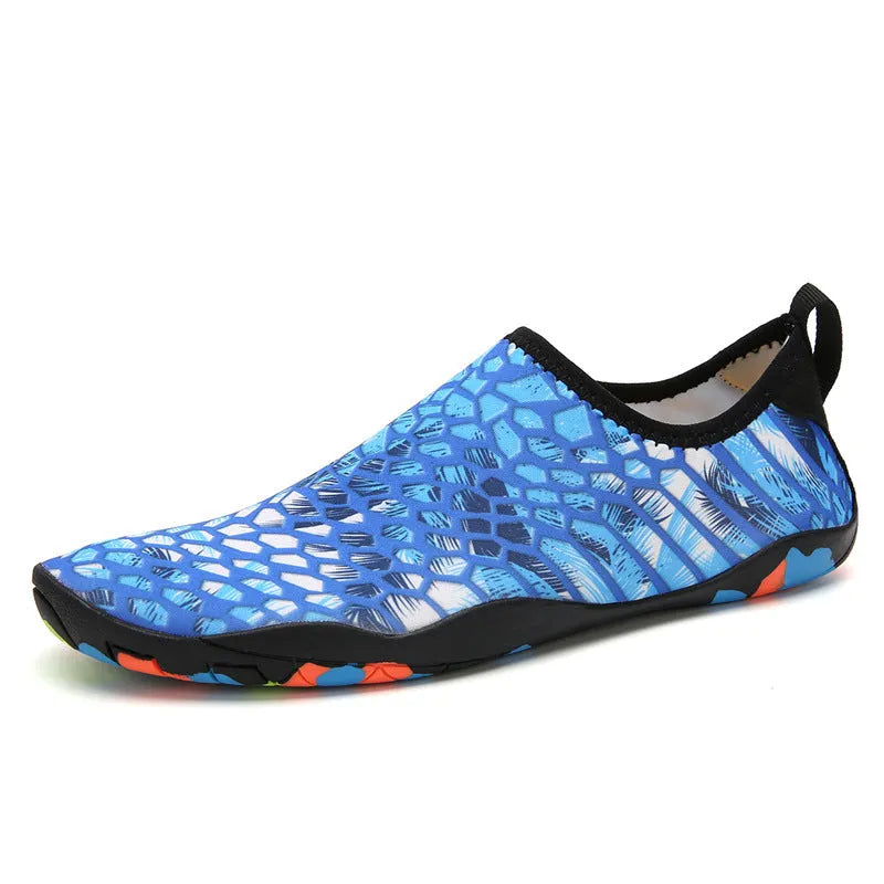 Blue and black Lycra fabric beach wading shoes with EVA foam soles on a sandy background.