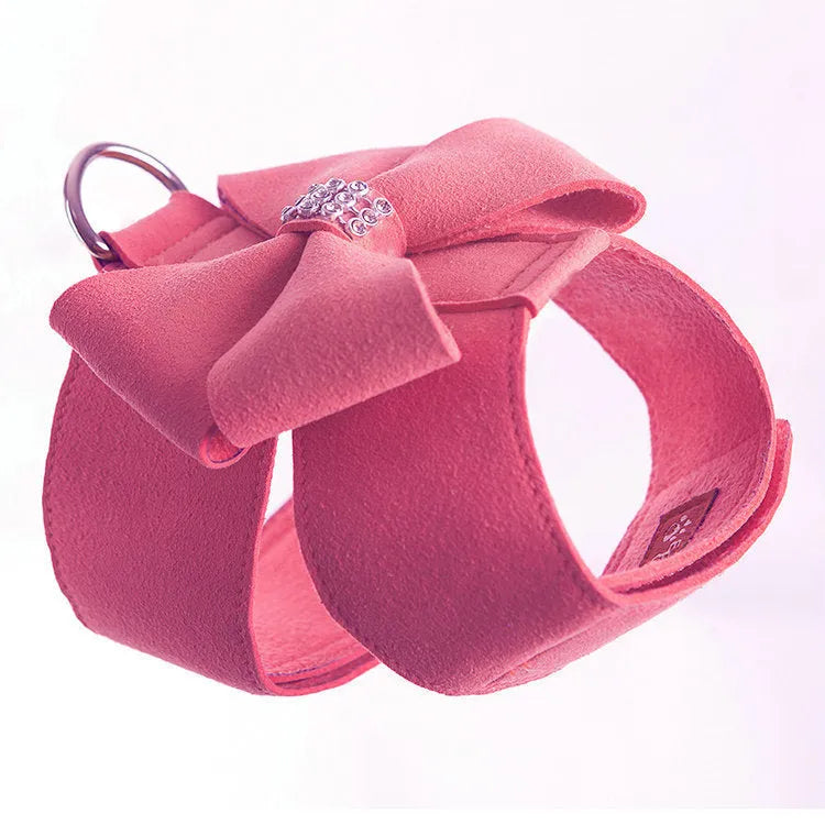 A pink dog harness with a white bowknot on the chest strap, shown on a small dog.