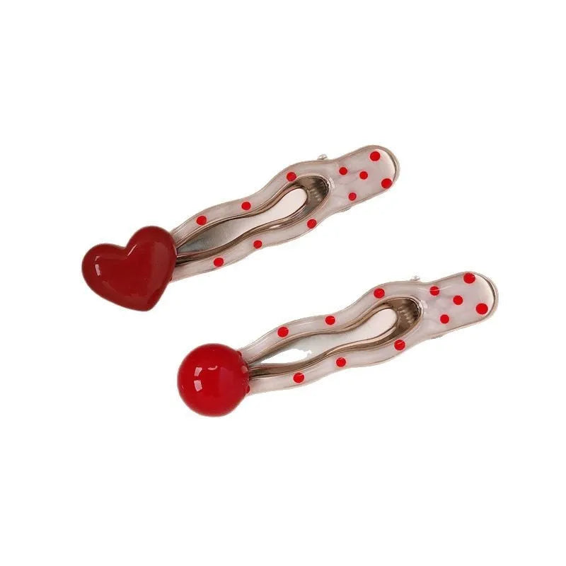 Red love heart-shaped hair clip with white polka dots and a green willow leaf decoration.
