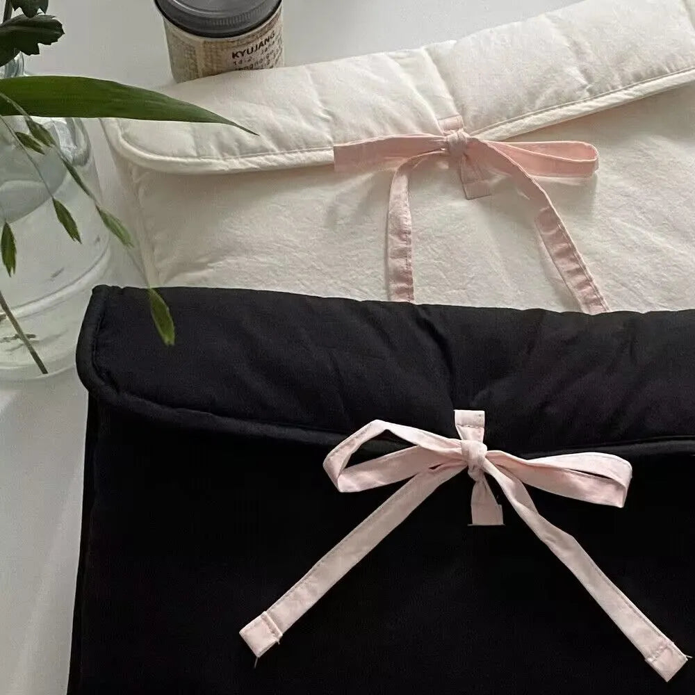 Women's black and white striped quilted laptop bag with a large ballet-style bow on the front.
