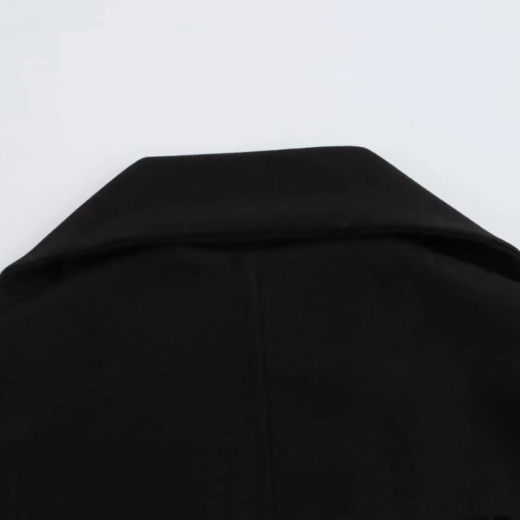 A woman wearing a long grey polyester coat with a detachable artificial fur collar and side pockets.
