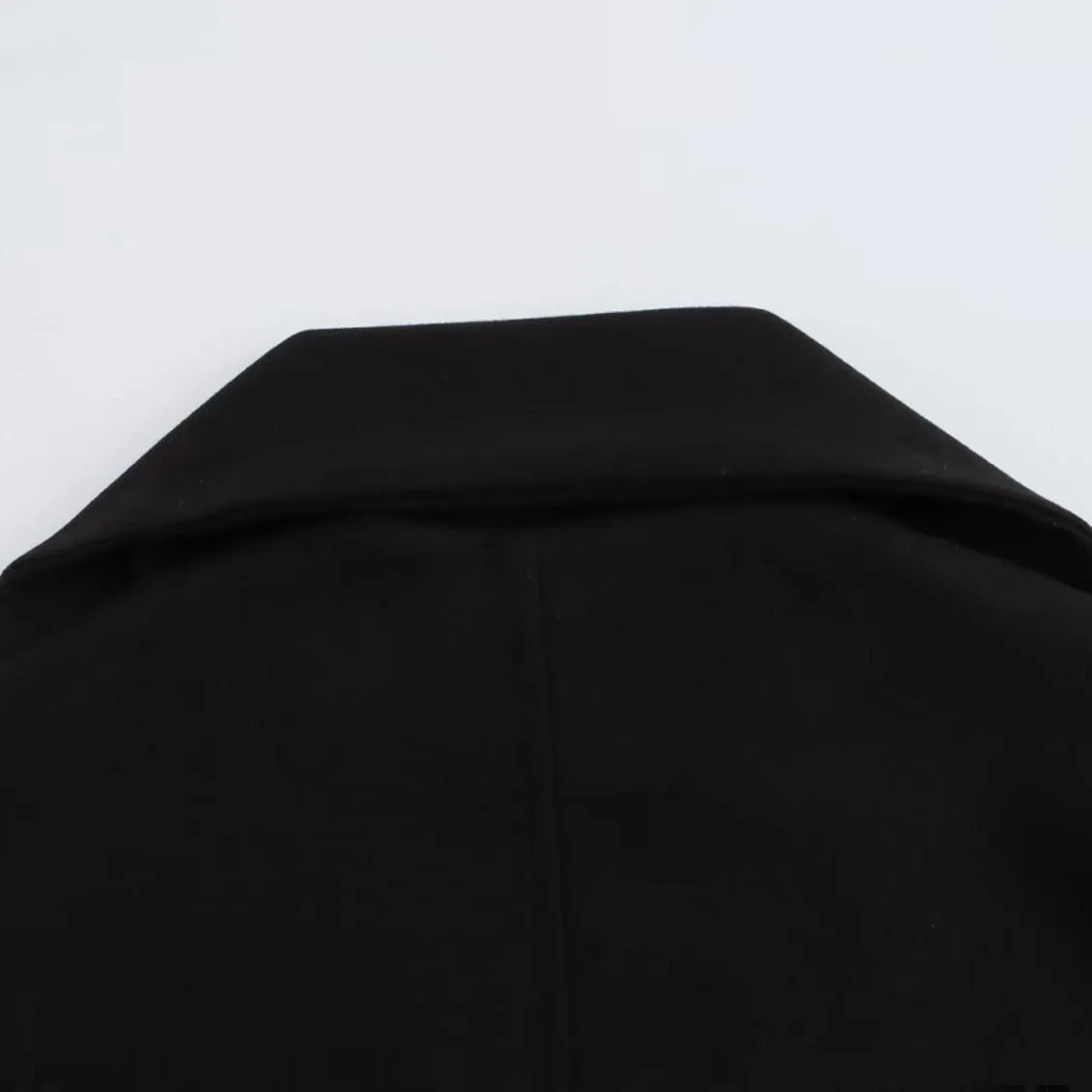 A woman wearing a long grey polyester coat with a detachable artificial fur collar and side pockets.