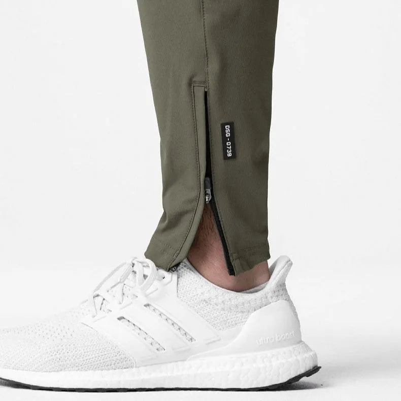 Men's loose grey running pants with ankle ties, laid flat to show mid-waist and full-length design.