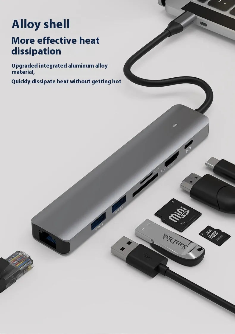 7-in-1 USB C card reader hub with multiple ports and SD card slots on a desk next to a laptop.