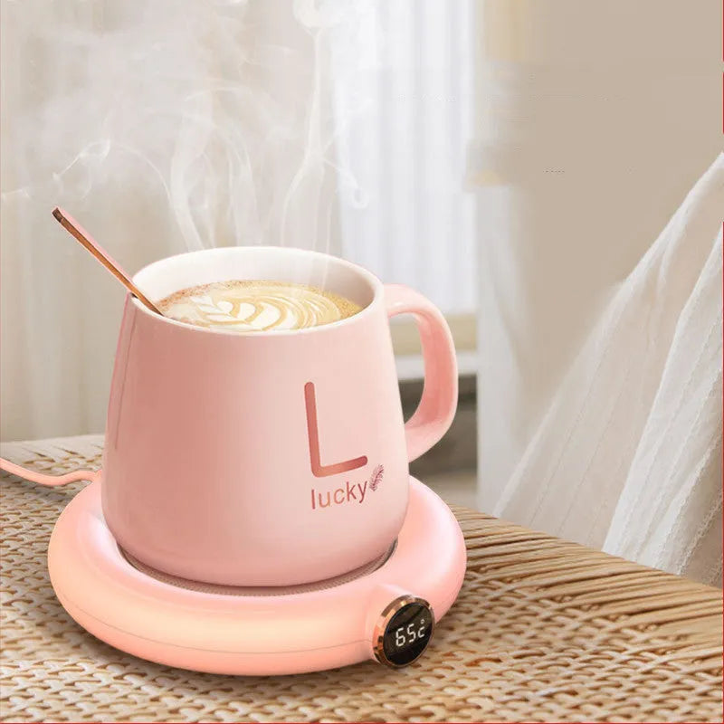 White USB cup warmer pad with LED display on a desk next to a mug.