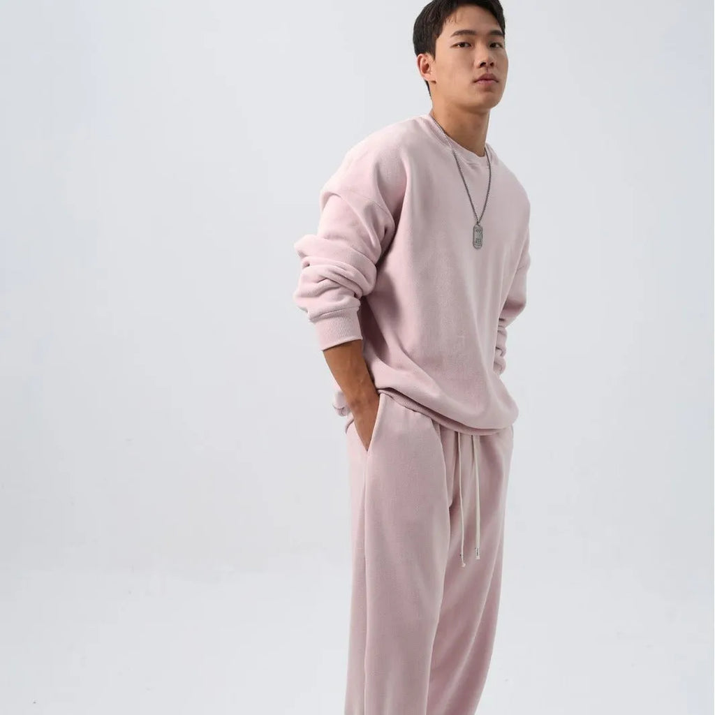 Man wearing a black polar fleece sports suit with a crew neck coat and loose trousers.