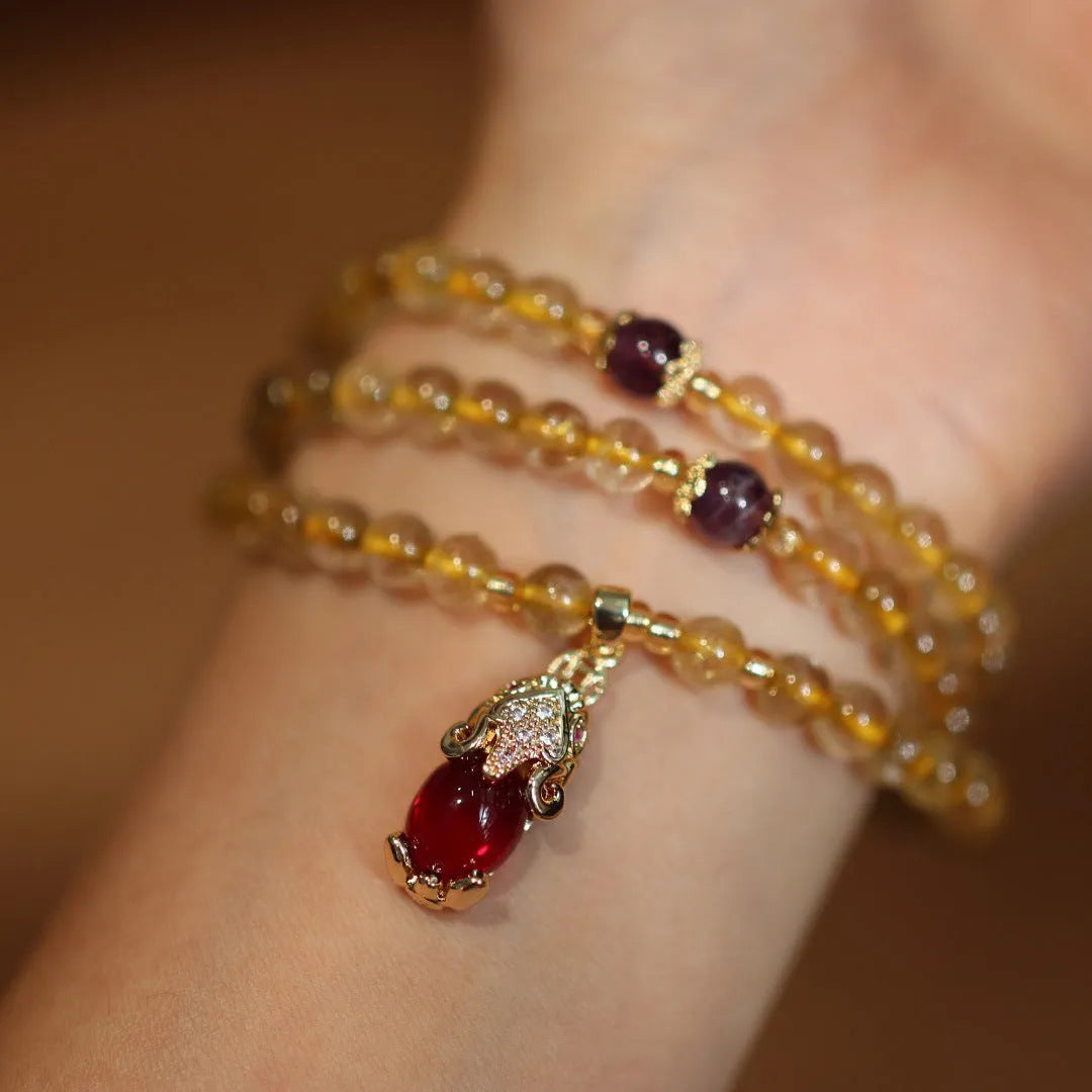 Handmade gold rutilated quartz bracelet with three-circle Chinese design and hanging chopsticks.
