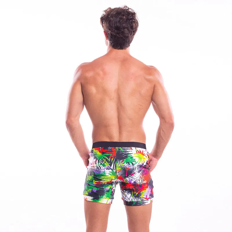 Men's spandex polyester swim shorts with elastic waist and drawstring on a beach background