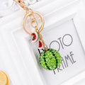Green watermelon-shaped metal keychain with sparkling crystal details on a white background.