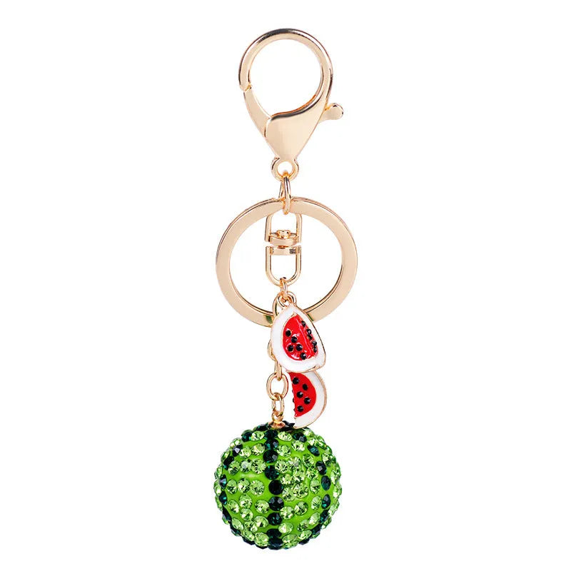 Green watermelon-shaped metal keychain with sparkling crystal details on a white background.
