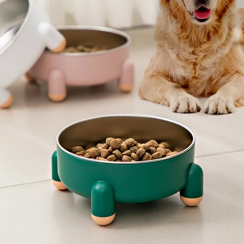 A green stainless steel pet bowl with a non-slip base and high foot, placed on a floor.