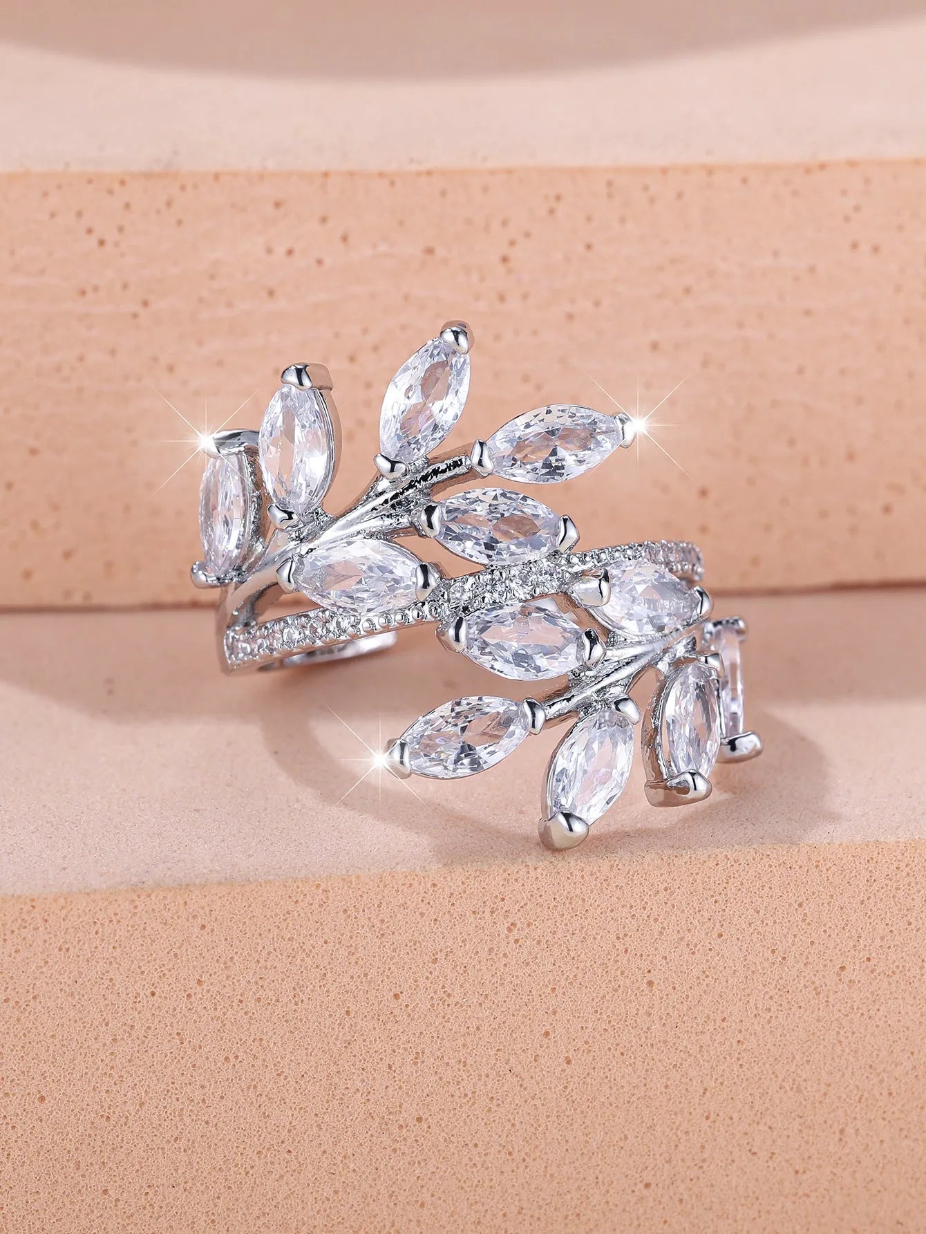 Adjustable open-ended leaf-shaped ring with zirconia stones on a copper band.