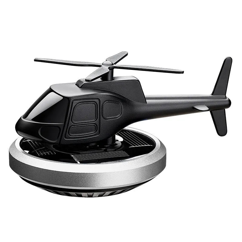 Silver solar-powered metal helicopter car air freshener with rotating blades on a dashboard.