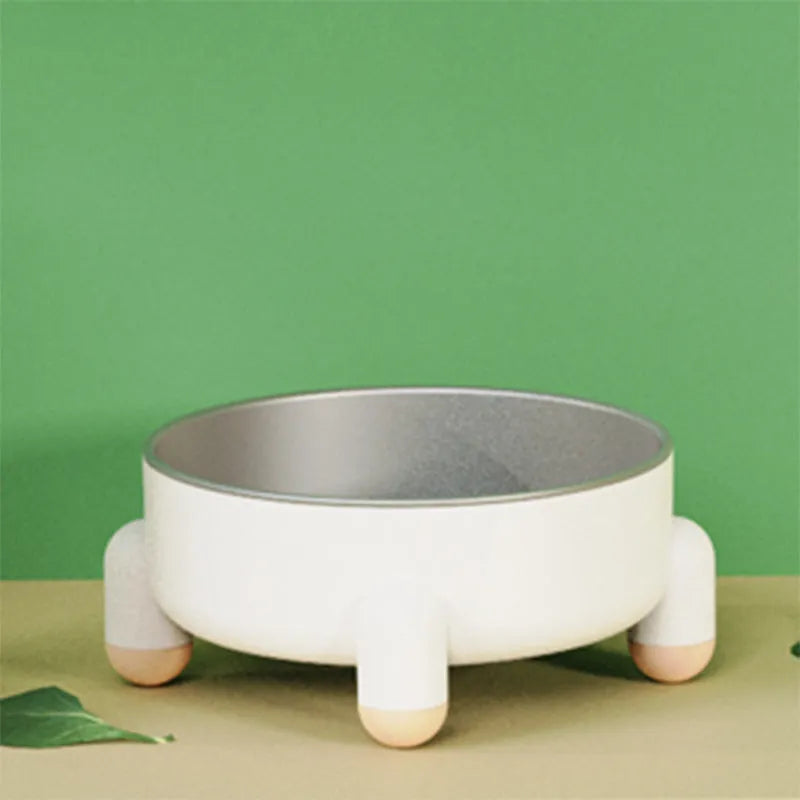 A green stainless steel pet bowl with a non-slip base and high foot, placed on a floor.