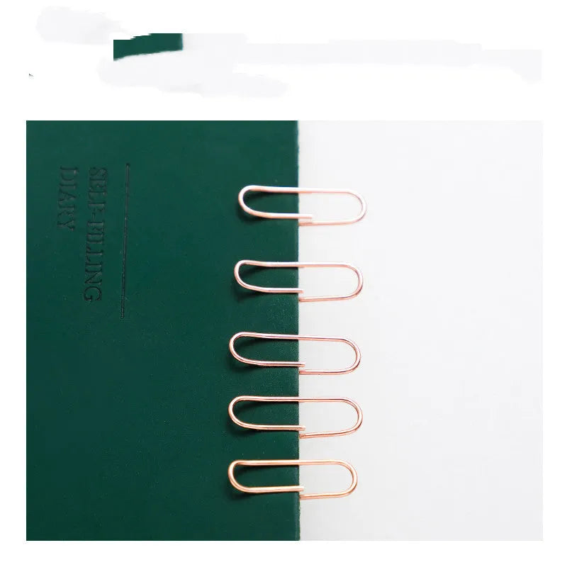 Box of 100 rose gold heart-shaped steel paper clips on a white background.