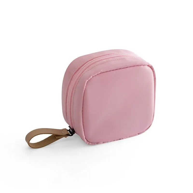 A blue cloth cube-shaped makeup storage bag with a plain pattern, sitting on a surface.