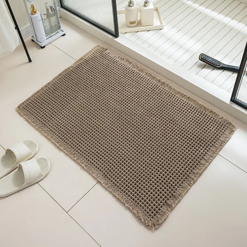 A square, checkered-pattern bathroom carpet in a choice of colours on a tiled floor.