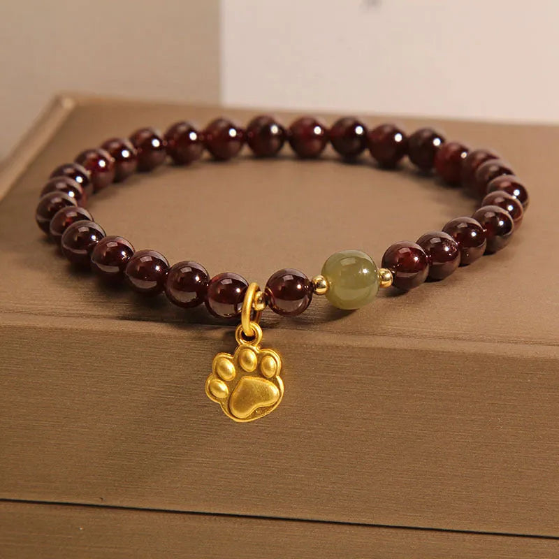 Women's adjustable crystal bracelet with a cat's paw shaped garnet stone centrepiece.