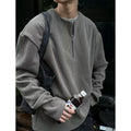 A grey loose-fitting long sleeve women's pullover top hanging flat.