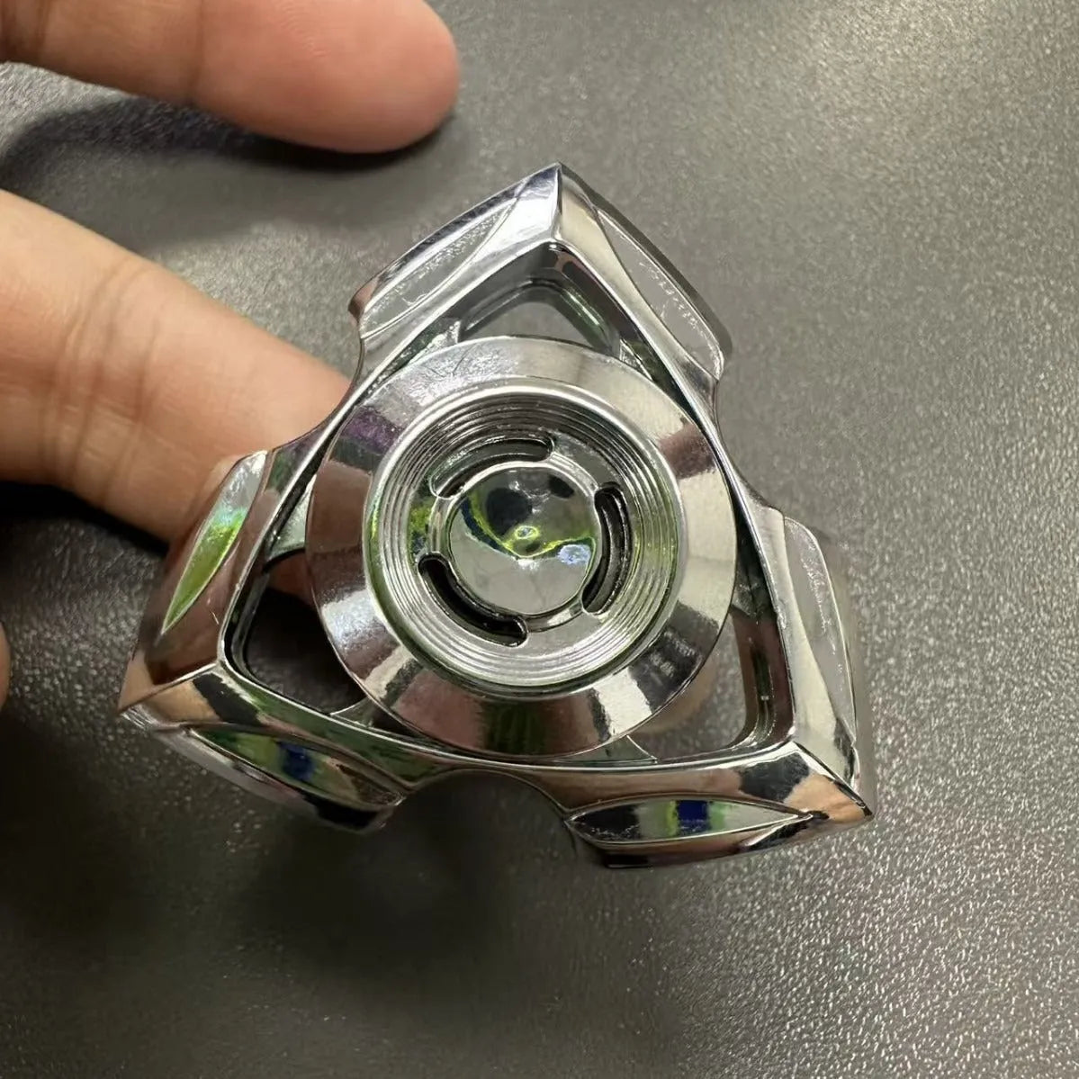 A silver alloy fingertip gyro decompression toy with a central spinning bearing.
