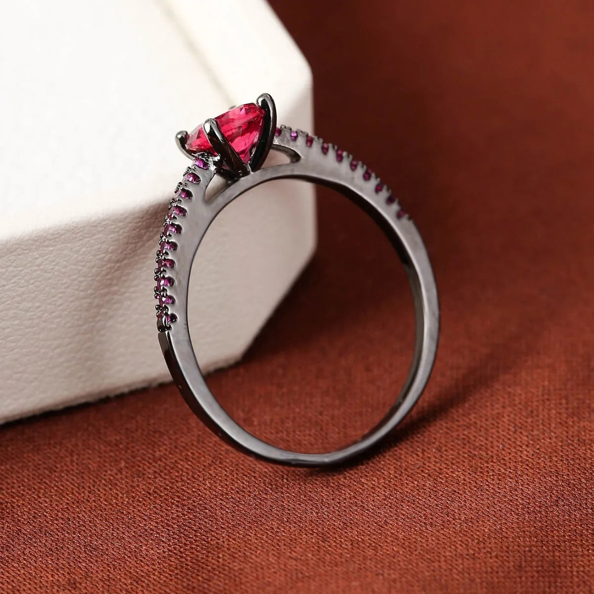 Geometric hexagon zircon ring in copper on a grey background, showing electroplated gold rose red finish.