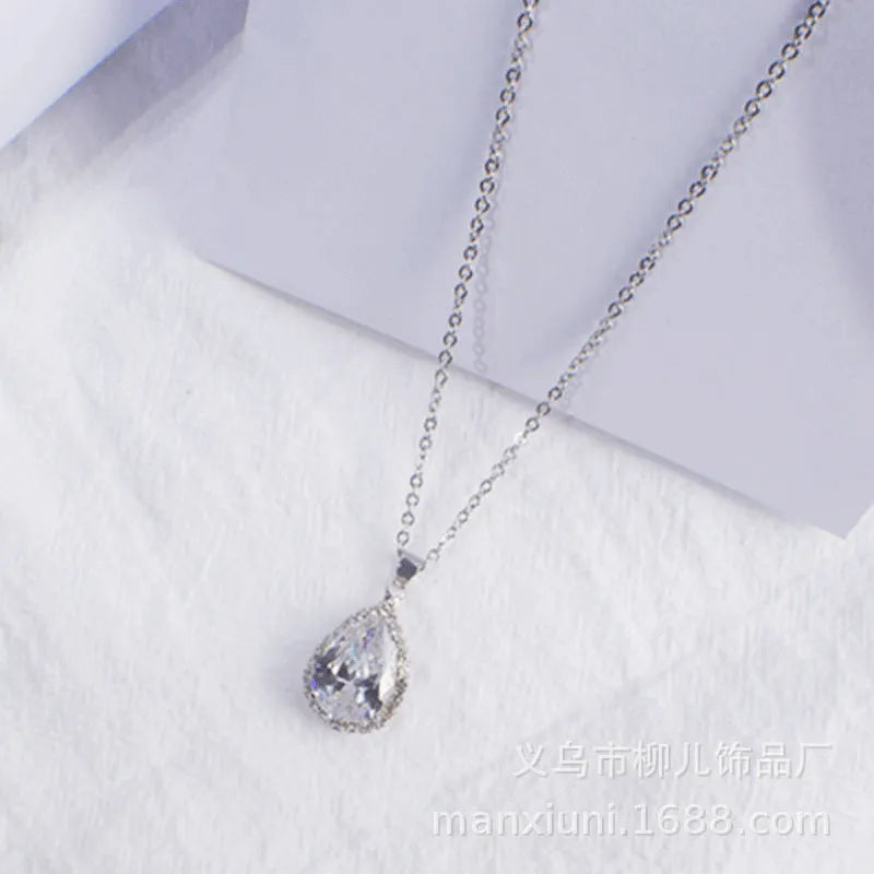 Close-up of a women's rose gold tone drop pendant necklace with pink rhinestone inlay on a model.