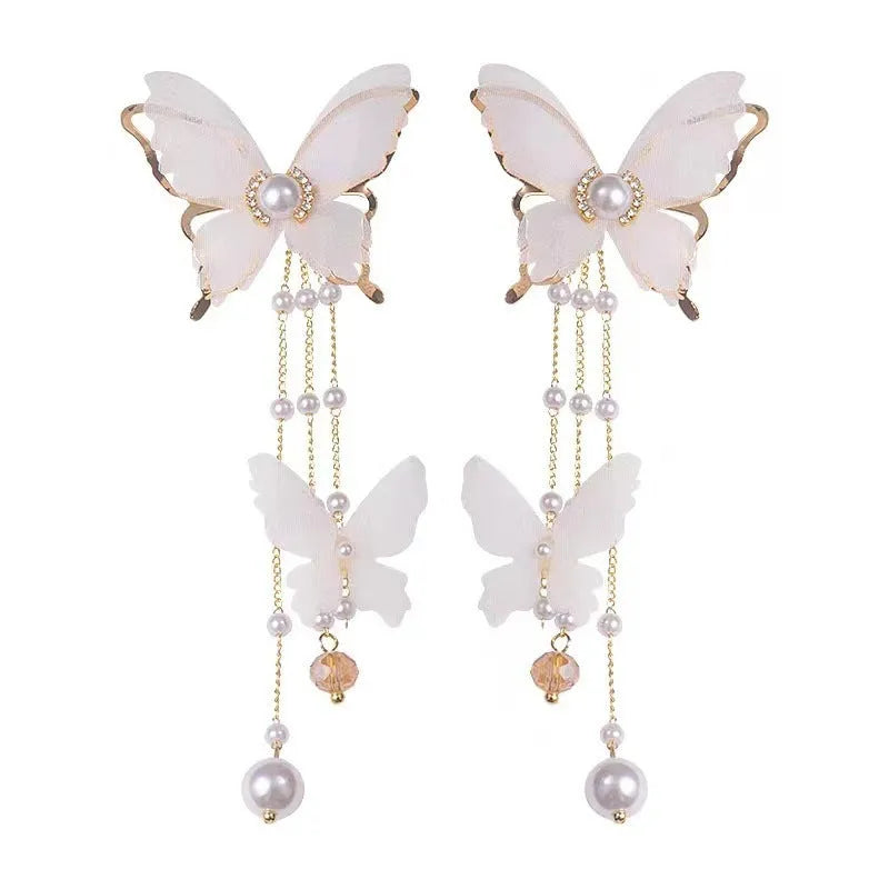 White butterfly-shaped earrings with dangling tassel, lace patterning, pearls, and clear rhinestones.