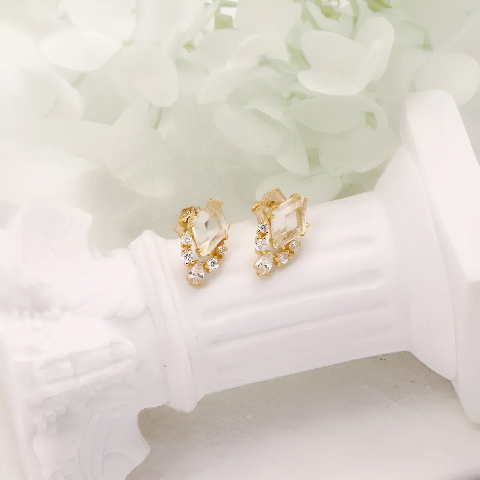 Geometric sterling silver earrings with sweet white crystal studs on white background