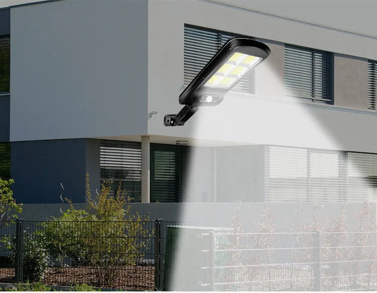 Black outdoor solar-powered security light with motion sensor on a wall.
