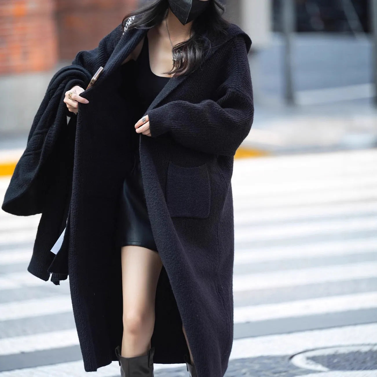 Long grey knitted women's cardigan with a hood, styled like a loose-fit trench coat.