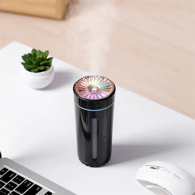 Black portable ultrasonic humidifier with colourful LED lights on a car cup holder.