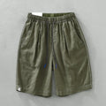 Man wearing green linen drooping shorts with a drawstring waist and mid-calf length.