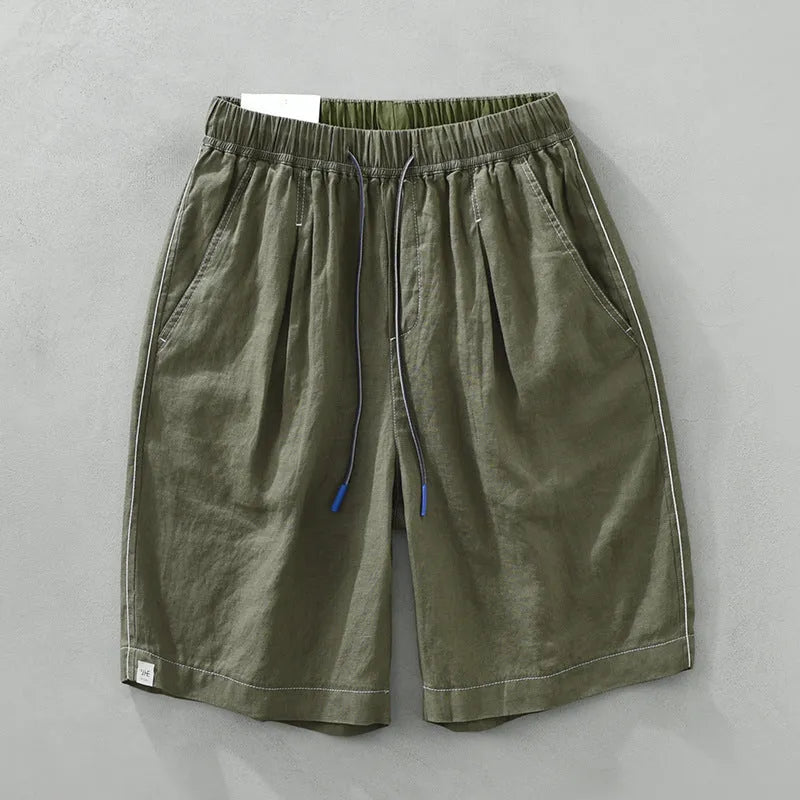 Man wearing green linen drooping shorts with a drawstring waist and mid-calf length.