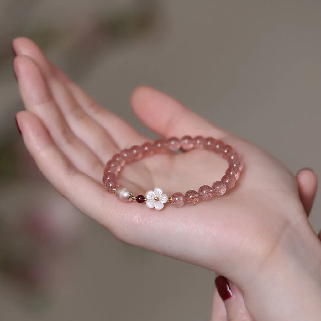 Strawberry quartz crystal bracelet with a peach blossom flower shape on a wrist.