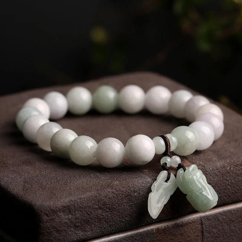 Green jade beaded bracelet with a hanging Maitreya Buddha charm on a wrist.