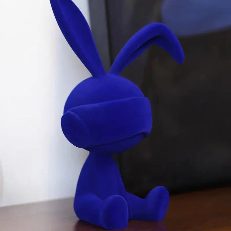 Small green resin suede blindfold rabbit table ornament on a wooden surface