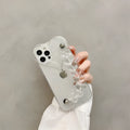 Transparent iPhone case with a love heart charm on a chain, on an iPhone.